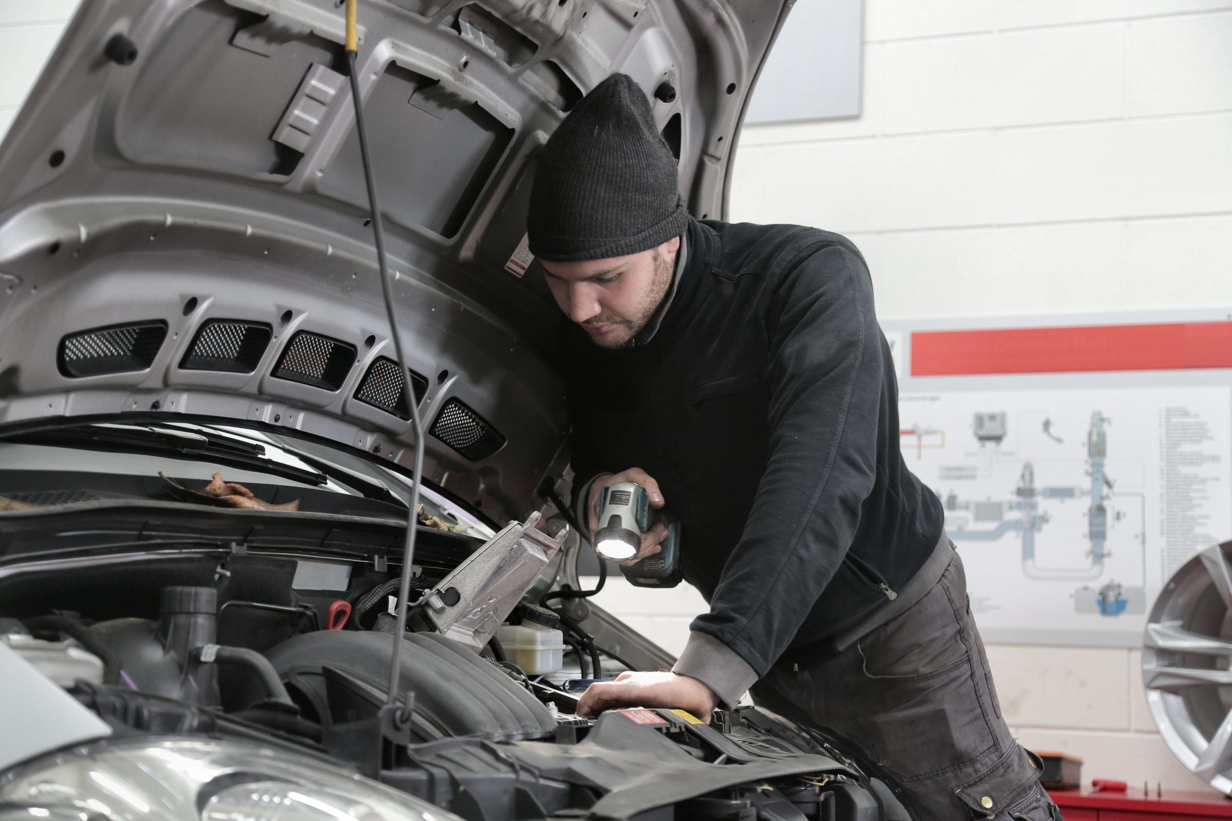 Technician working under the hood of a car in a workshop