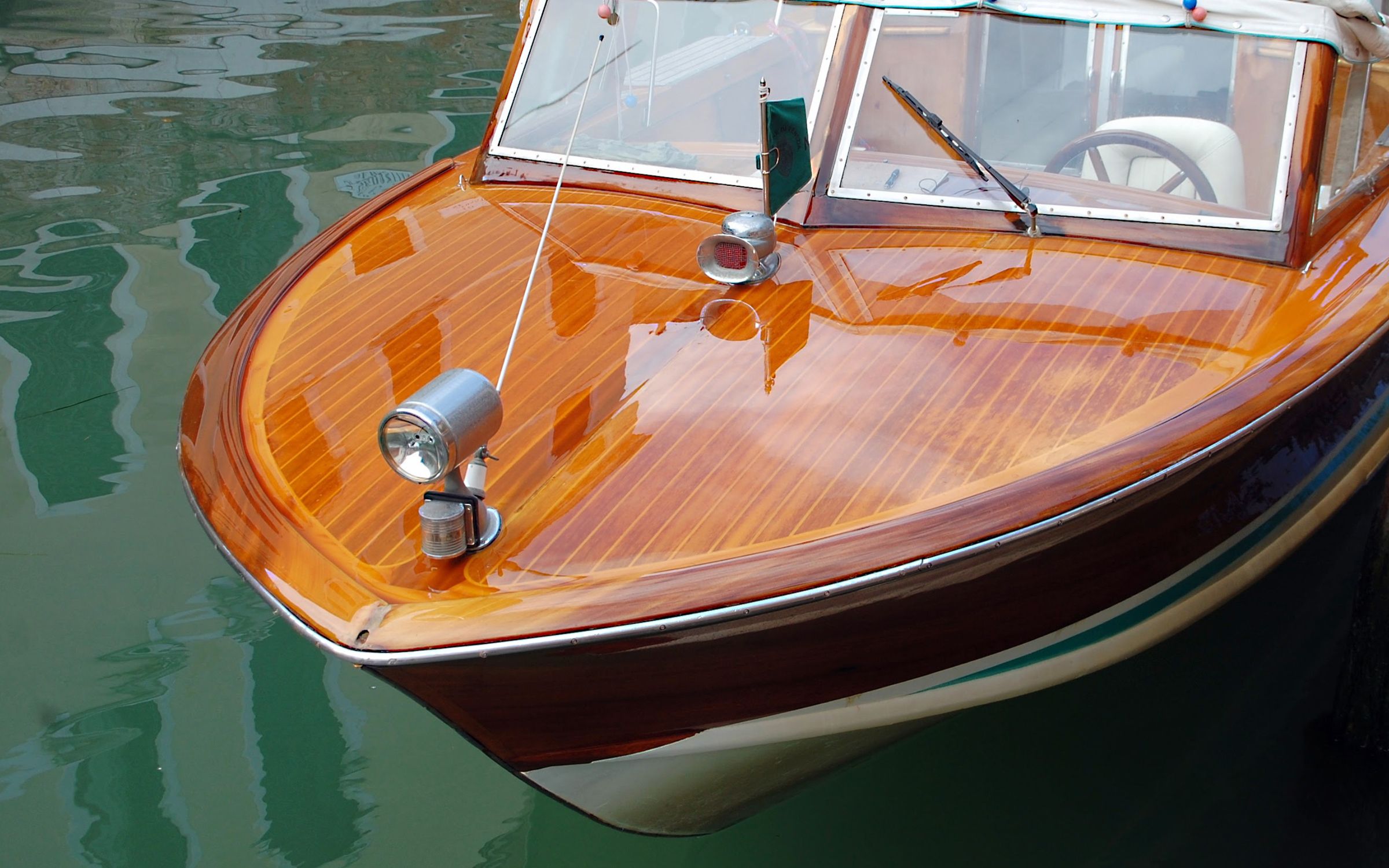 Varnished mahogany runabout foredeck reflecting on calm water